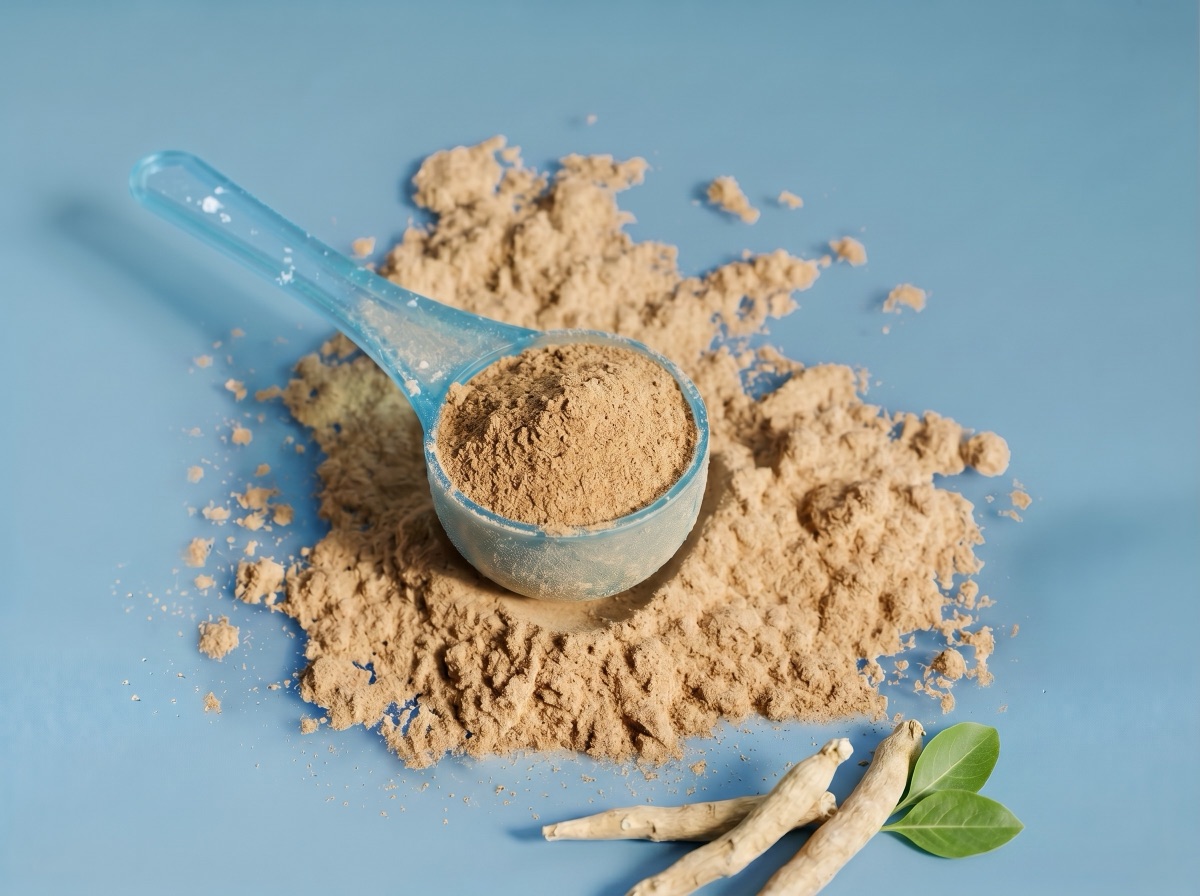 A translucent blue scoop of beige Ashwagandha KSM-66 extract with dried roots and green leaves at the bottom edge on a muted blue studio background.