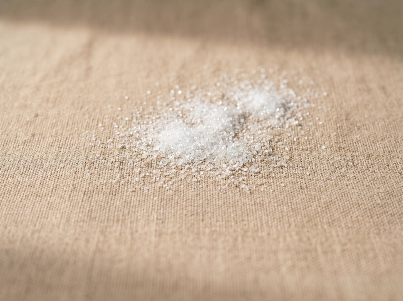 A small mound of fine white crystalline L-tyrosine powder on natural linen.