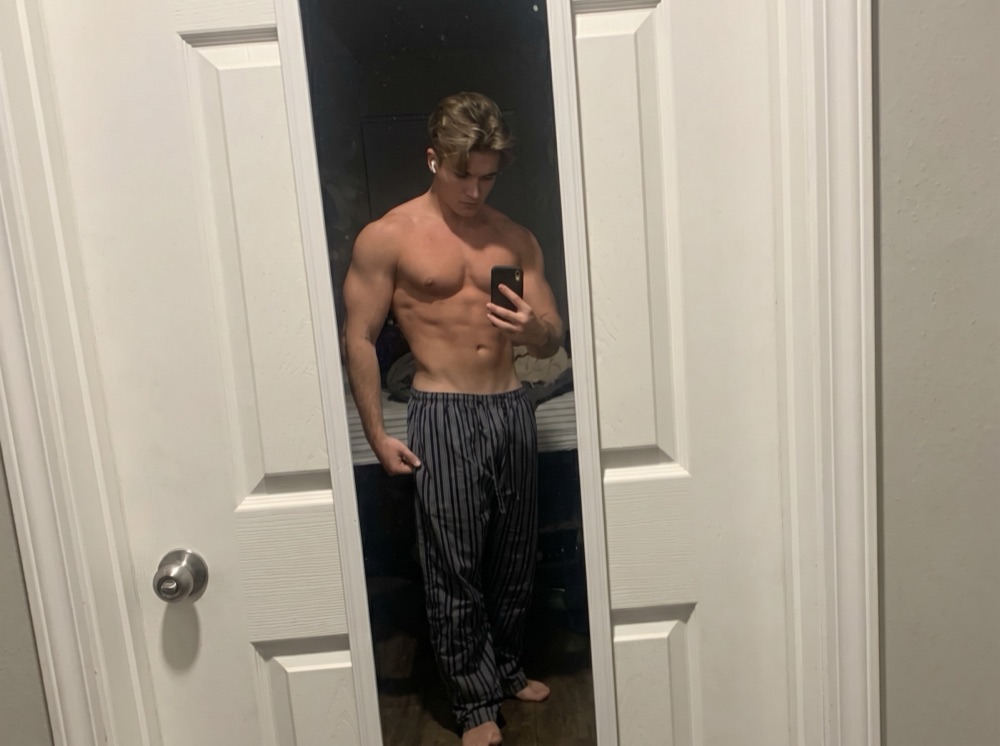Before photo: young man in pajama pants taking a mirror selfie, lean baseline build, evening lighting.